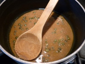 In a small saucepan, heat the anchovies, anchovy oil, olive oil and sesame oil over moderate heat, stirring until the anchovies dissolve, 2 to 3 minutes. Turn off the heat and stir in the vinegar, capers and mustard.