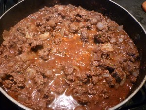 Once the meat is browned, stir in 1/4 tsp. cinnamon, 1/4 tsp. nutmeg, 1/2 tsp. herbs de Provence or herbs fines, and 2 Tbsp. dried parsley. Add 8-oz. tomato sauce and 1/2 cup red wine (or beef broth). Simmer for 20 minutes. Let cool. Stir in one beaten egg.